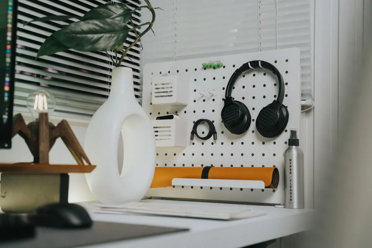 A contemporary workspace featuring a pegboard with headphones and stylish decor.