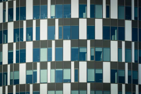 Close-up of a modern office building facade with geometric patterns and glass windows.