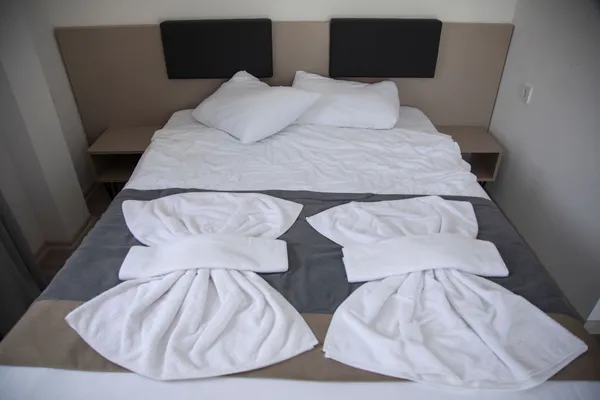 Hotel bedroom with neatly arranged bed and artistic towel design, creating a welcoming ambiance.